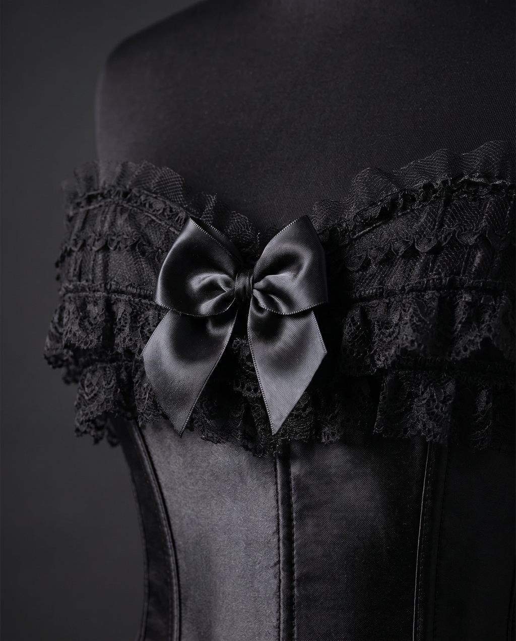 Close-up of the ruffled lace neckline and satin bow on a black corset
