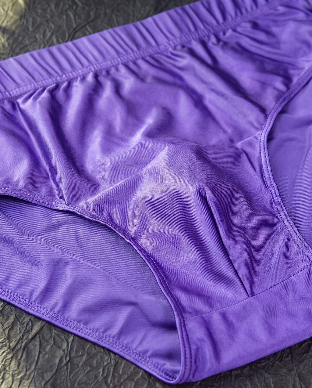 Macro close-up of the wide self-fabric waistband and glossy satin-finish fabric