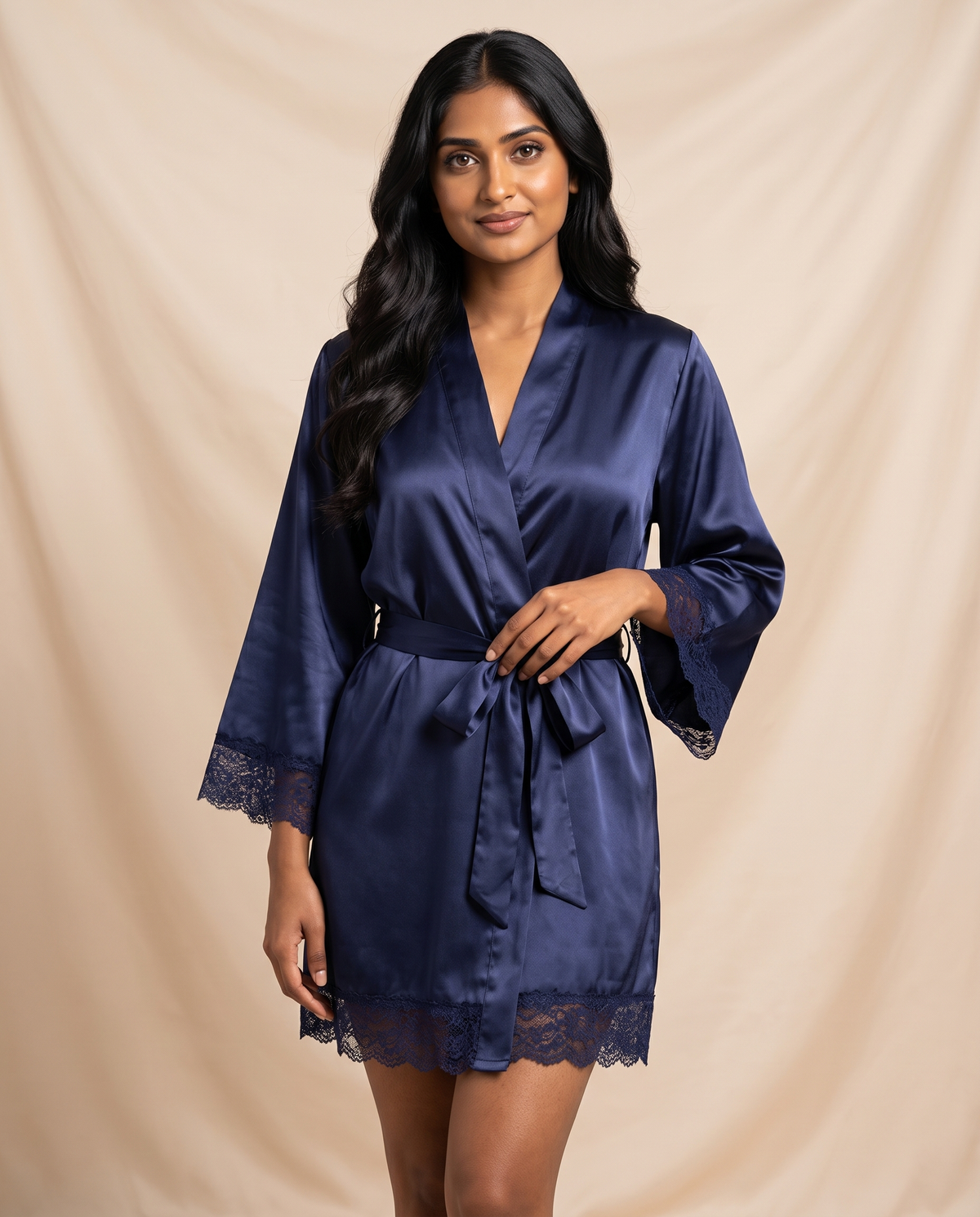 Woman standing in a navy satin wrap robe with lace trim, belted at the waist